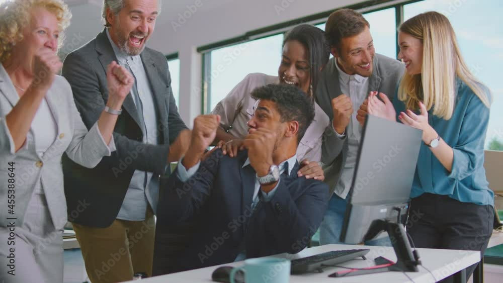 Mixed-races team of office workers cheering in front of computer screen and celebrating successful work finish of project. Multiethnic male and female business people applauding as having great result Mixed-races team of office workers cheering in front of computer screen and celebrating successful work finish of project. Multiethnic male and female business people applauding as having great result