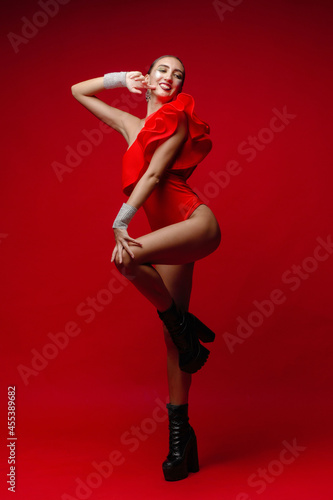 a slender young girl in red clothes on a red background in a photo studio © Ruslan
