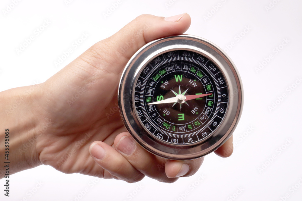 Close up of hand holding magnetic silver metal compass Close up of hand holding magnetic silver metal compass