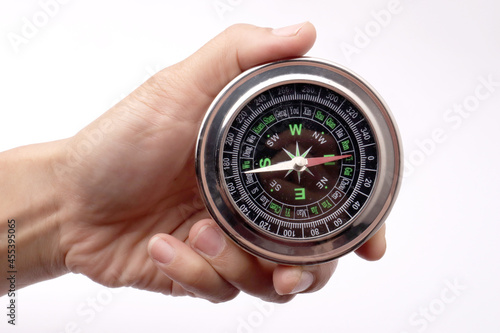 Close up of hand holding magnetic silver metal compass
