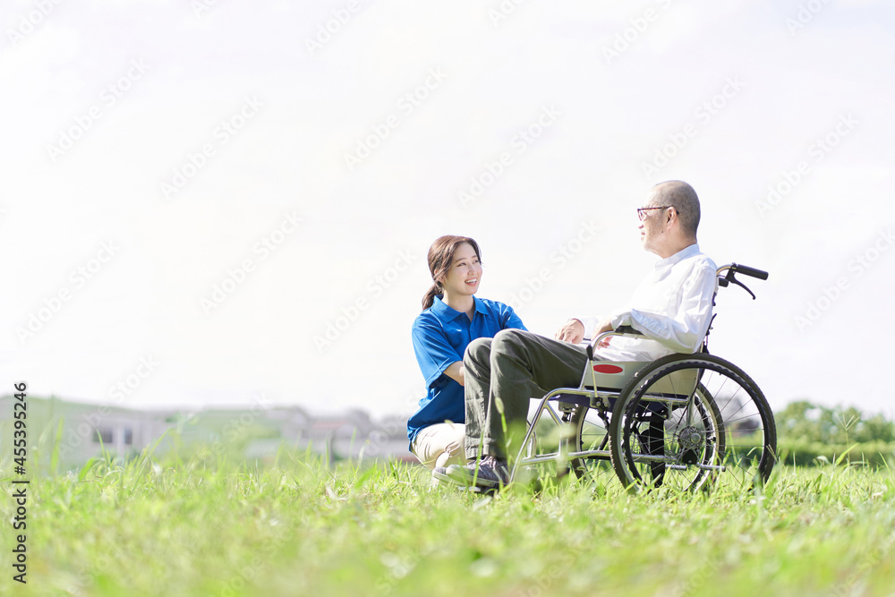 芝生で会話をする高齢者と介護士