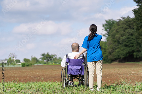畑を見る高齢者と介護士 