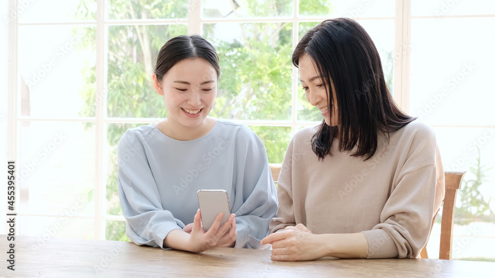 スマートフォンを一緒に使う母と娘 スマートフォンを一緒に使う母と娘