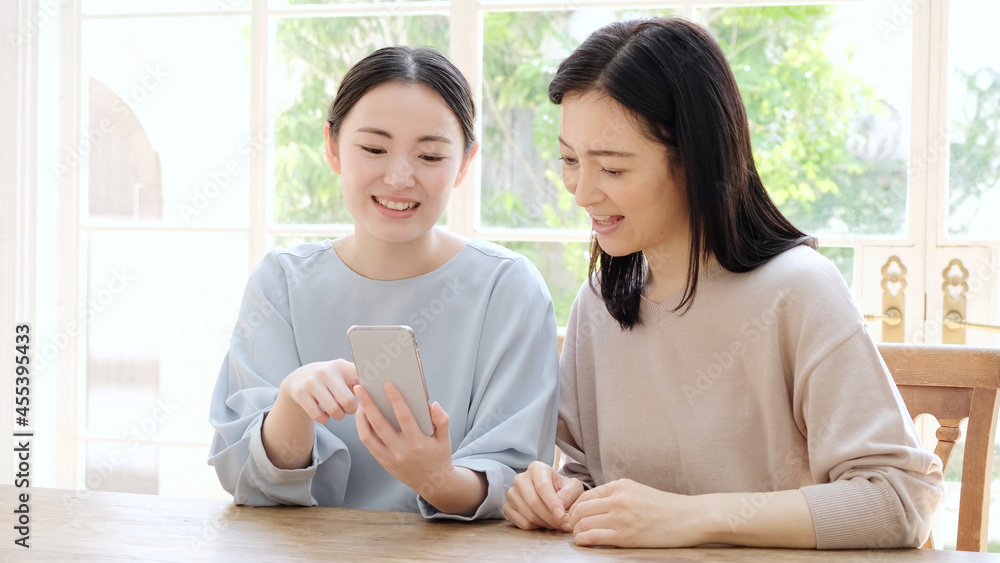 スマートフォンを一緒に使う母と娘 スマートフォンを一緒に使う母と娘
