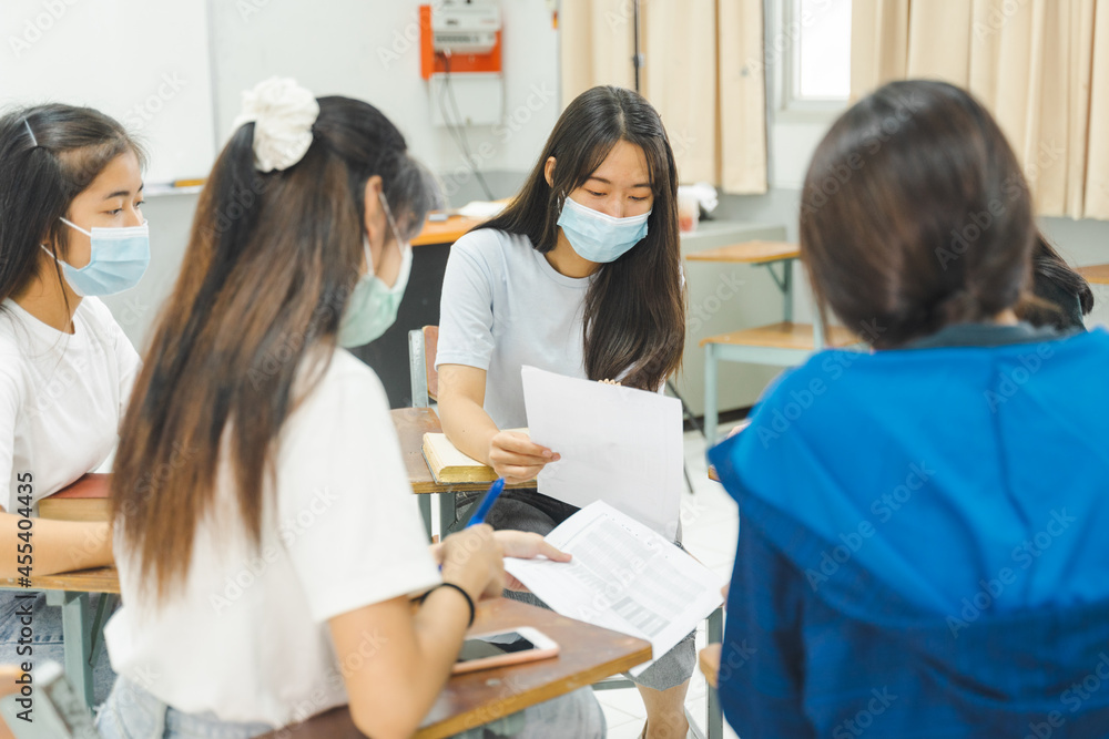 Group asian university students wear protective face mask discuss project in the classroom Group asian university students wear protective face mask discuss project in the classroom