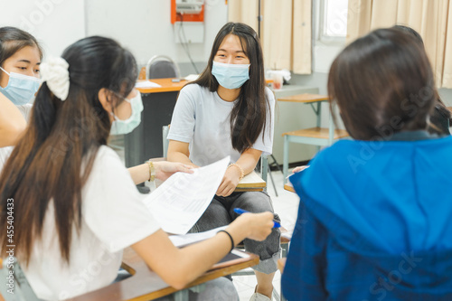 Group asian university students wear protective face mask discuss project in the classroom