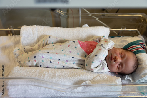 Newborn baby girl lays in baby incubator in hospital