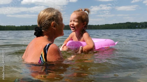 Wallpaper Mural Video shot of grandmother with small charming granddaughter bathe in lake, summer vacation in lake, jumping, bathing, swimming
 Torontodigital.ca
