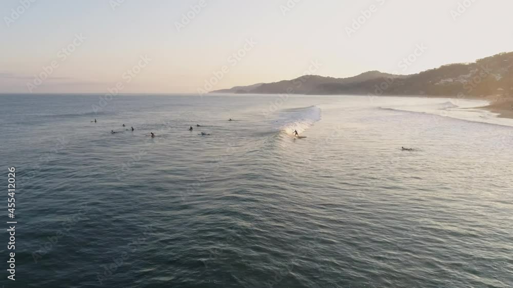 Aerial following surfer as they ride wave in towards shore at sunset, 4K Aerial following surfer as they ride wave in towards shore at sunset, 4K
