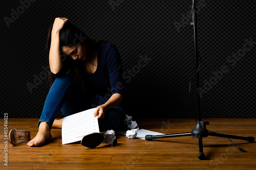 Bild auf Leinwand Pity Asian woman singer exhausted sit under mic with crushed paper in hand, stre