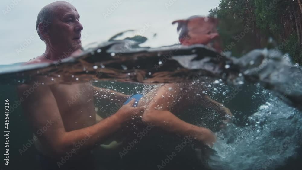 Stock Family swim in lake. Preteen boy learns swimming and has fun in the lake with grandfather. Underwater view of the family jumping and swimming in the lake | Adobe Stock 