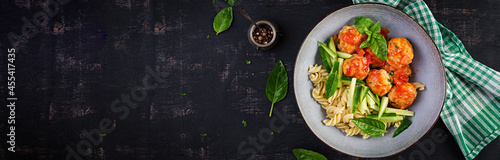 Italian pasta. Fusilli with meatballs, cucumber and basil on dark background. Dinner. Slow food concept. Top view, banner