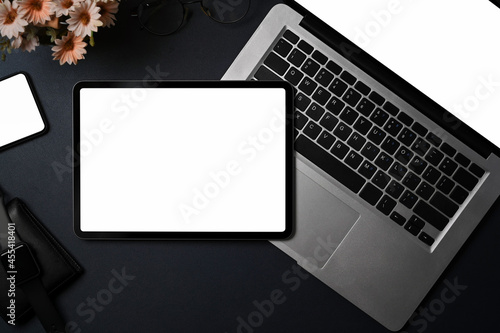 Above view dark modern workspace with digital tablet, laptop computer and smart phone on black leather.