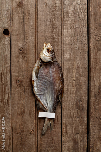 Sun-dried bream with paper label on tail on wooden background