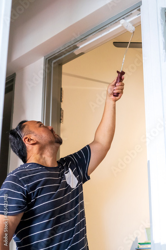Valokuva Man painting door frame with a roller