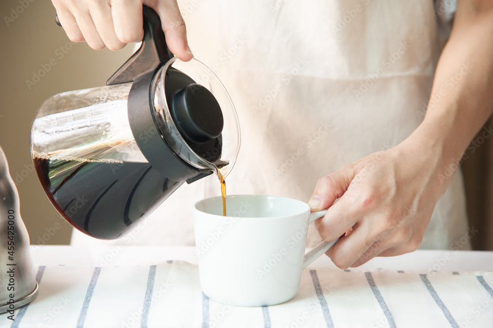 Crop of barista pouring black coffee in white and empty cup at home