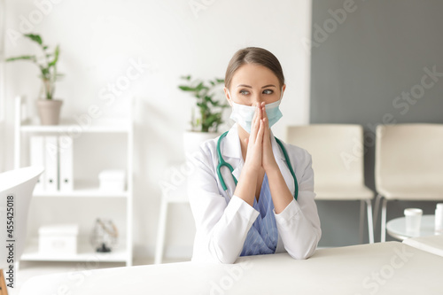Praying female doctor in cl...