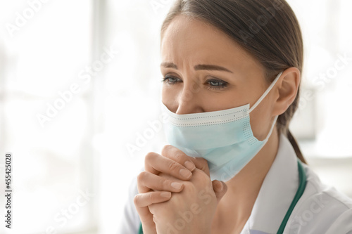 Praying female doctor in cl...