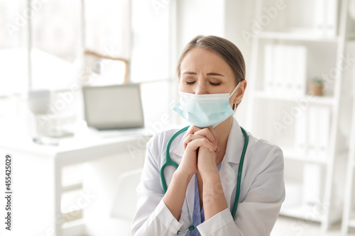Praying female doctor in cl...