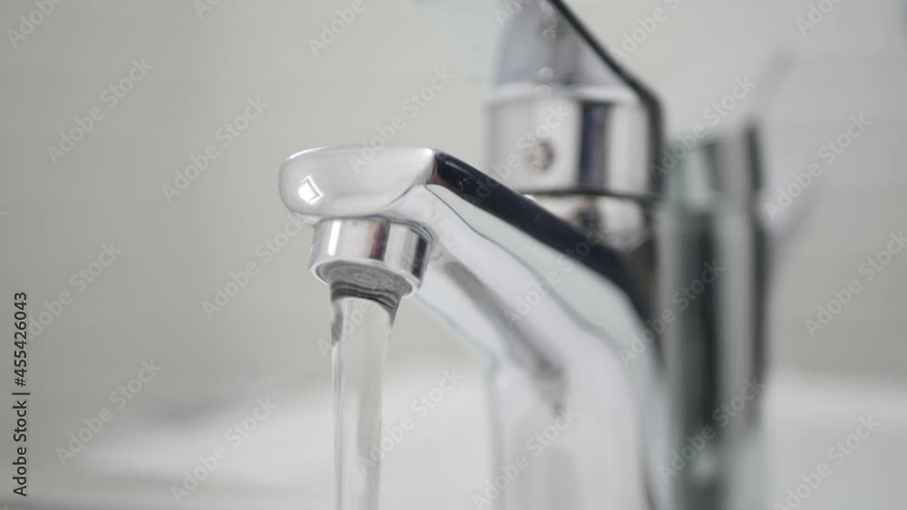 Medical Person Wearing Protective Gloves in Hands Opening the Water Tap from a Sink in Bathroom. Medical Person Wearing Protective Gloves in Hands Opening the Water Tap from a Sink in Bathroom.