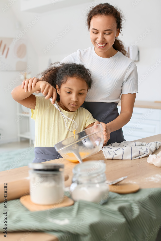 African-American little girl and her mother cooking in kitchen African-American little girl and her mother cooking in kitchen