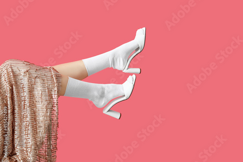 Legs of stylish young woman on color background