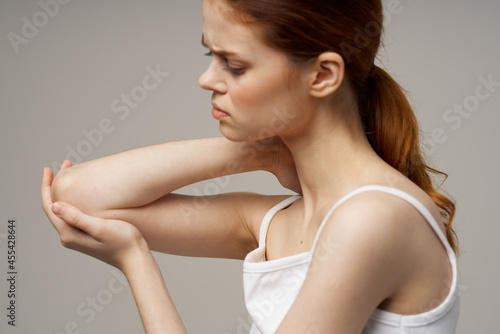 disgruntled woman elbow pain arthritis chronic disease light background