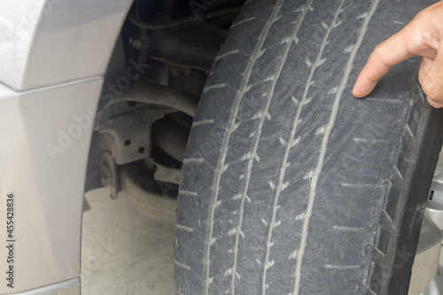 Man finger pointing to damage on tire tread. Tire tread problems by tire pressure improper, Wheel alignment