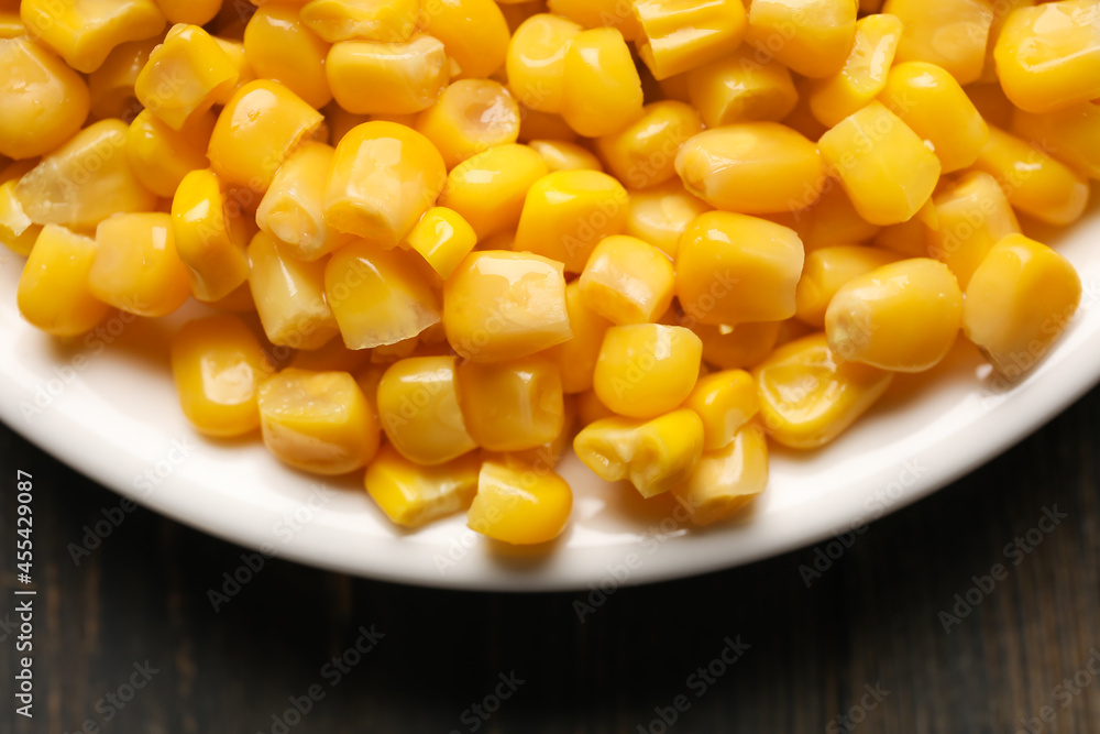 Plate with corn kernels on wooden background, closeup Plate with corn kernels on wooden background, closeup