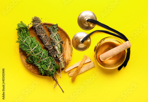 Tibetan singing bowl, karatalas, Palo Santo and herbs for aura cleansing on color background photo