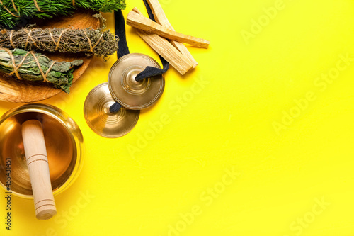 Tibetan singing bowl, karatalas, Palo Santo and herbs for aura cleansing on color background photo