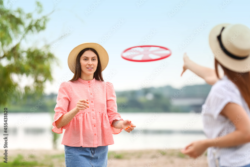 Fototapeta premium Beautiful young women playing frisbee outdoors