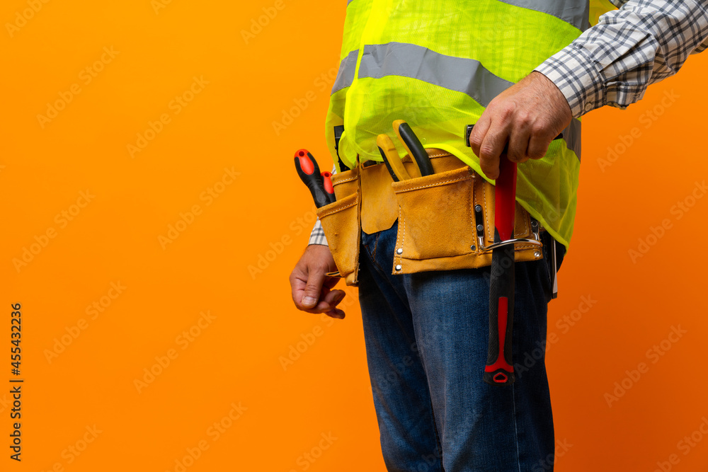 Studio shot of unknown handyman with hands on waist and tool belt with construction tools Studio shot of unknown handyman with hands on waist and tool belt with construction tools