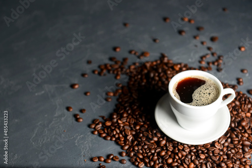 Warm cup of coffee with coffee beans over black background. Coffee time, copy space web design banner.