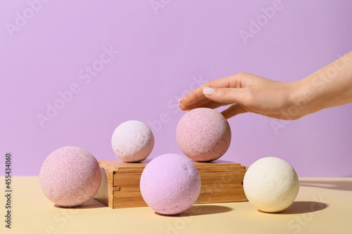 Female hand with lavender bath bombs on color background