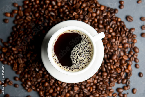 Warm cup of coffee with coffee beans over black background. Coffee time, copy space web design banner. © zhinna