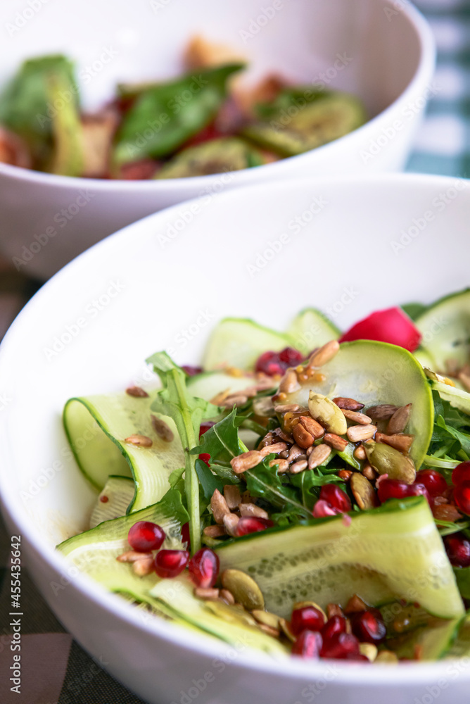 A large dish with a grilled zucchini salad with fresh cucumbers, radish, pomegranate seeds and fresh arugula. A large dish with a grilled zucchini salad with fresh cucumbers, radish, pomegranate seeds and fresh arugula.