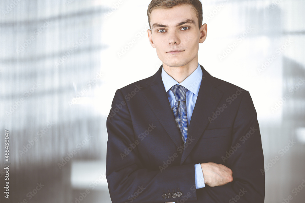 Young businessman wearing suit and tie, while standing in the office. Business success concept nowadays Young businessman wearing suit and tie, while standing in the office. Business success concept nowadays