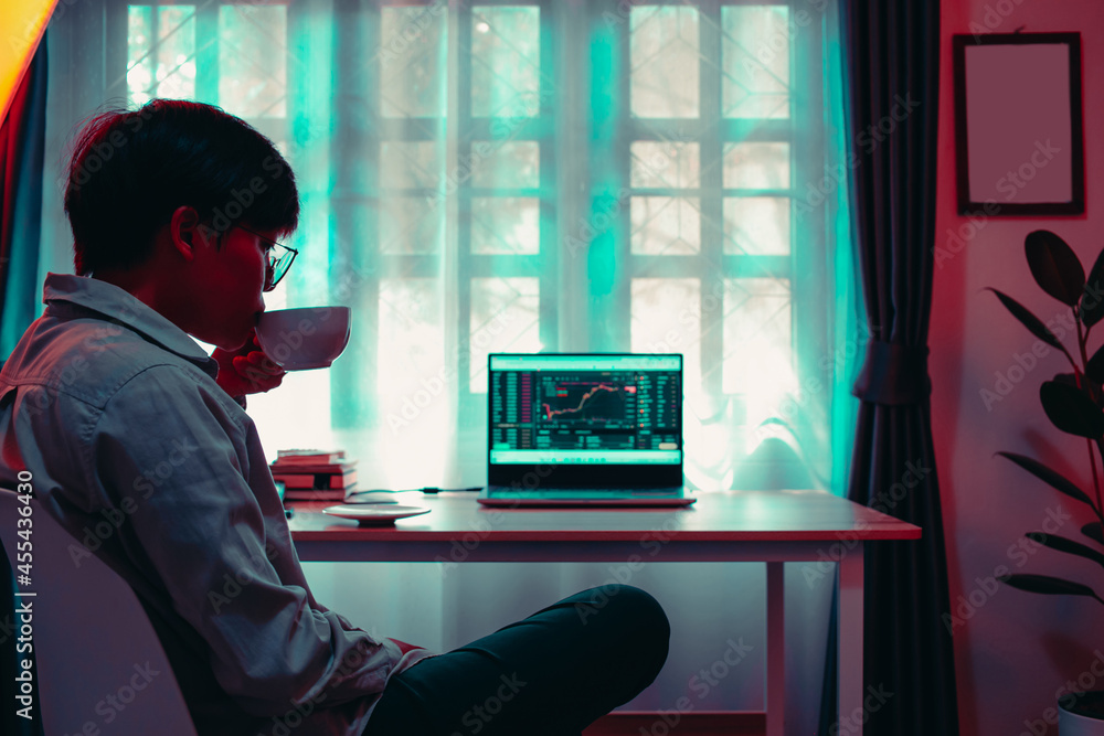 business Asian woman 30s looking graphs cryptocurrency trading platforms on laptop and drinking hot coffee with the calculator, notebook on the desktop table at on vivid colorful office home business Asian woman 30s looking graphs cryptocurrency trading platforms on laptop and drinking hot coffee with the calculator, notebook on the desktop table at on vivid colorful office home