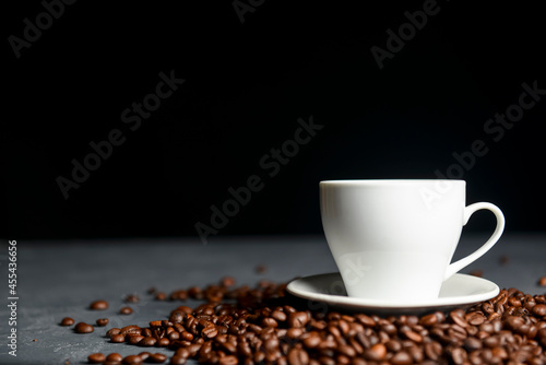 Warm cup of coffee with coffee beans over black background. Coffee time, copy space web design banner.