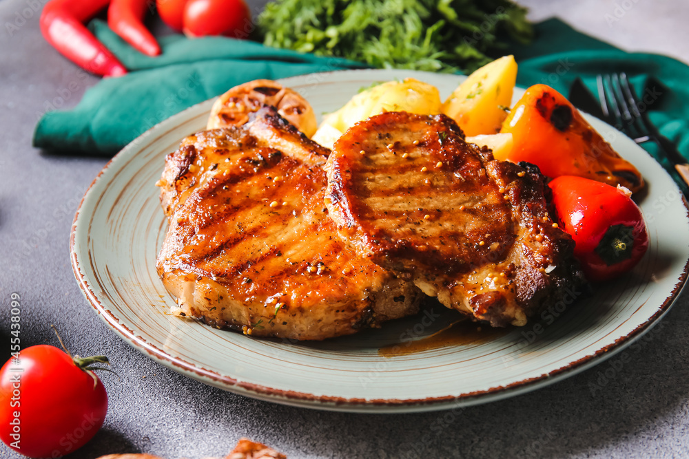 Plate with tasty pork steaks and grilled vegetables on table Plate with tasty pork steaks and grilled vegetables on table