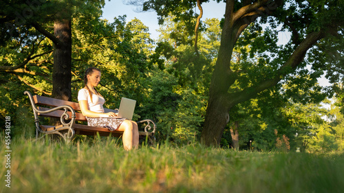 Work laptop outdoor. Student woman with computer, tablet in summer nature park. Girl does business with online technology outside. Electronic gadgets distance learning concept.