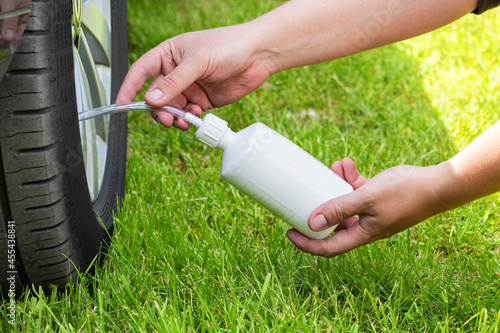 A man pours a car emergency sealant to puncture the wheels. Repairing a puncture of a wheel on the road. Close-up