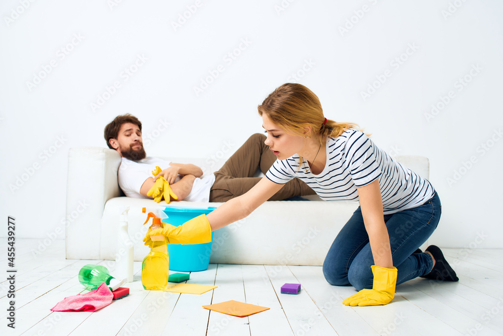 married couple near the sofa cleaning supplies light background married couple near the sofa cleaning supplies light background