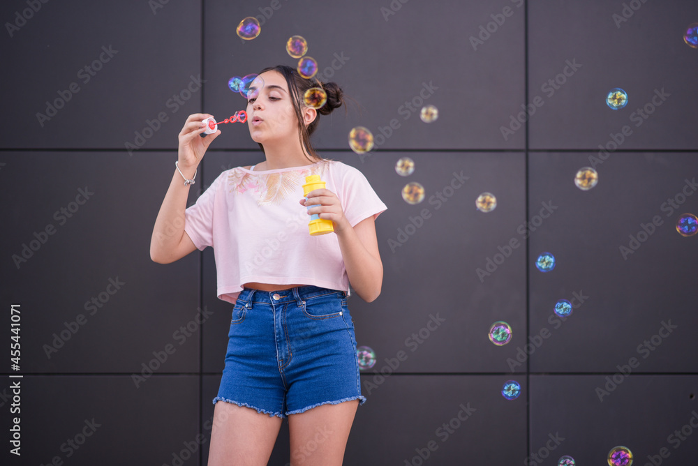 Stylish teen girl blowing soap bubbles