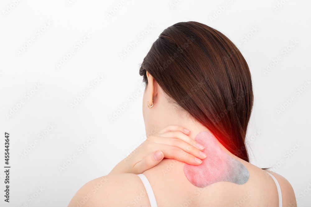 Medical anesthetic plaster on the cervical spine of a girl. Muscle spasm and pain treatment concept. Copy space for text Medical anesthetic plaster on the cervical spine of a girl. Muscle spasm and pain treatment concept. Copy space for text