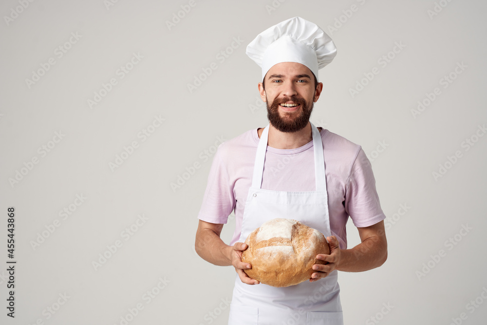 bearded man in a white apron with bread in his hands baking light background bearded man in a white apron with bread in his hands baking light background