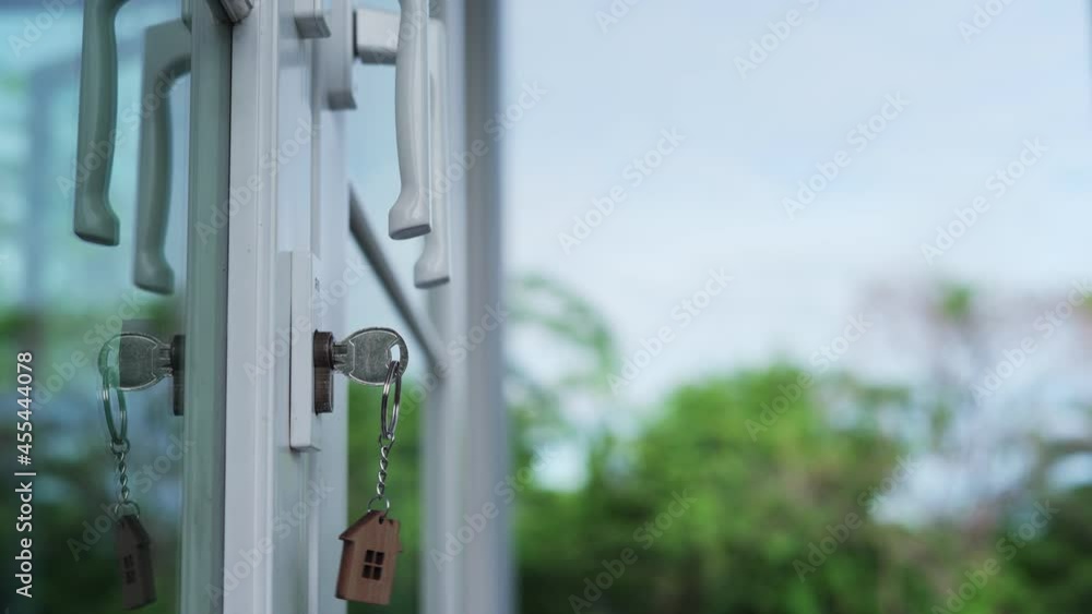 Landlord for house concept. The house key for unlocking a new house is plugged into the door. The wooden keychain was moving as the wind blew. Landlord for house concept. The house key for unlocking a new house is plugged into the door. The wooden keychain was moving as the wind blew.