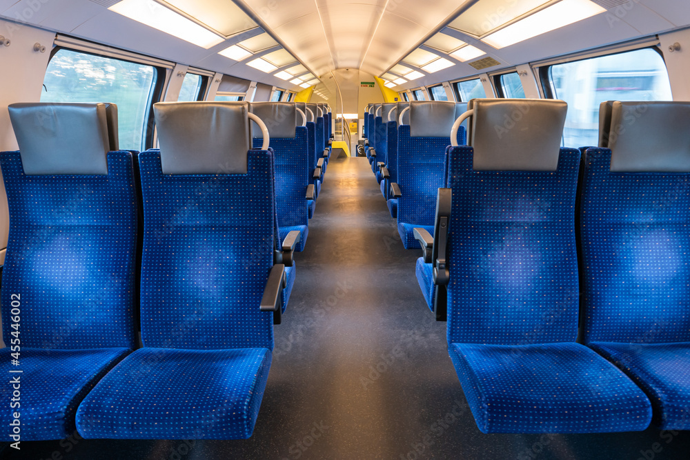 Fototapeta premium Empty blue seats inside train cabin, corridor view, no people.