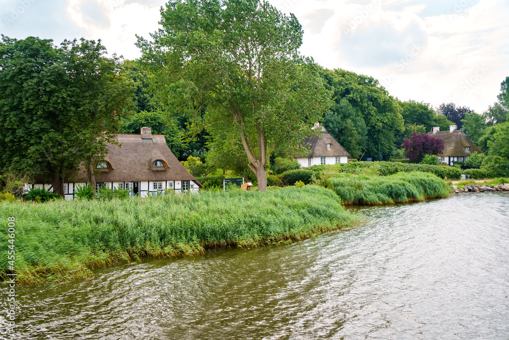 Obraz premium Beautiful Schlei region in Germany, Schleswig Holstein. German landscape in summer. Schlei river and typical houses with thatching, water reed roofs. Sieseby village